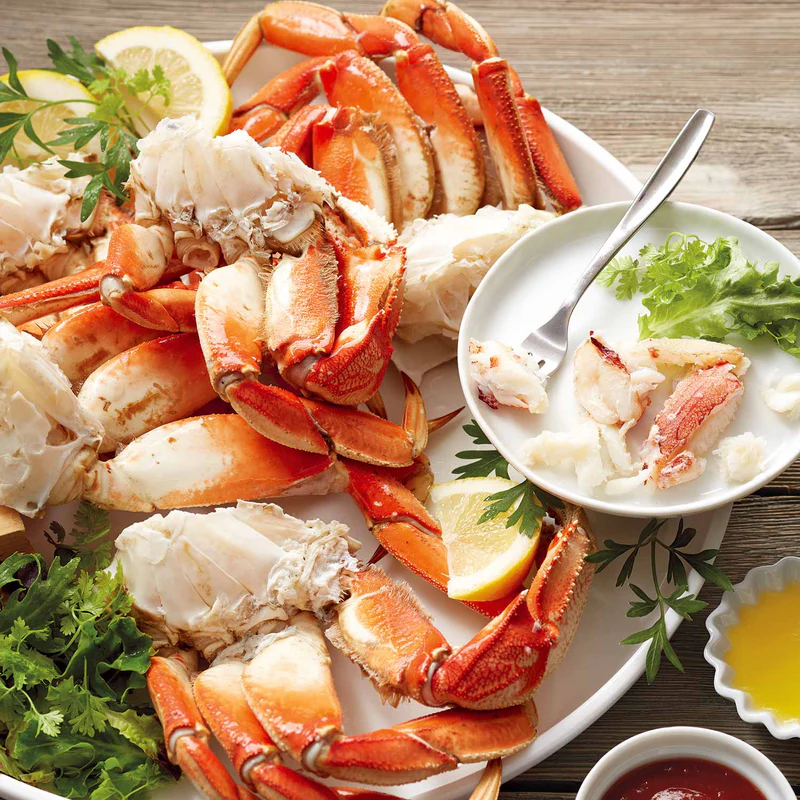 Cooked Dungeness crab clusters on a platter with lemon and butter
