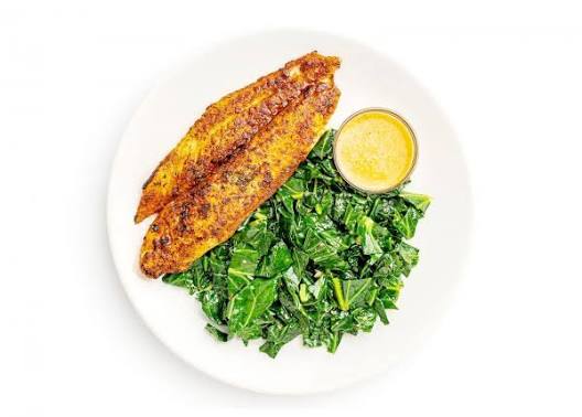 Seasoned Swai fillets with greens and sauce on a white plate