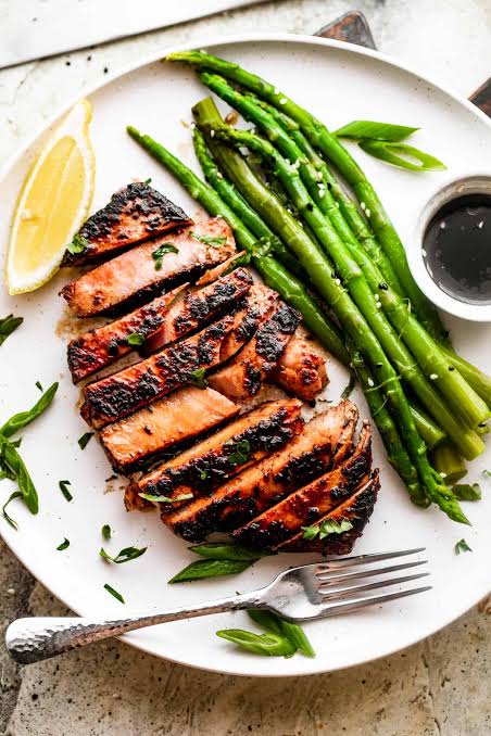 Seared tuna steak with asparagus on a white plate
